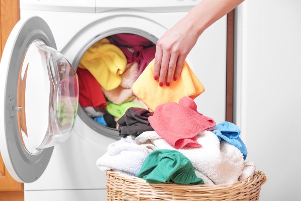 front-load washing machines top-load washers which is better woman hand taking laundry out of the washer basket with colorful clothes